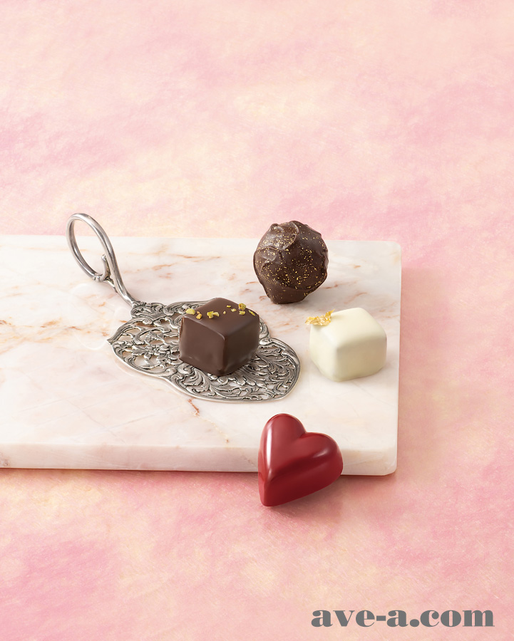 薄いピンク模様の背景に大理石のお皿を置いてその上にチョコレートを並べて撮影